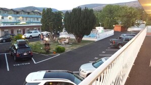 A parking lot with several cars, a visitor parking area, and a building with a white fence in the background.