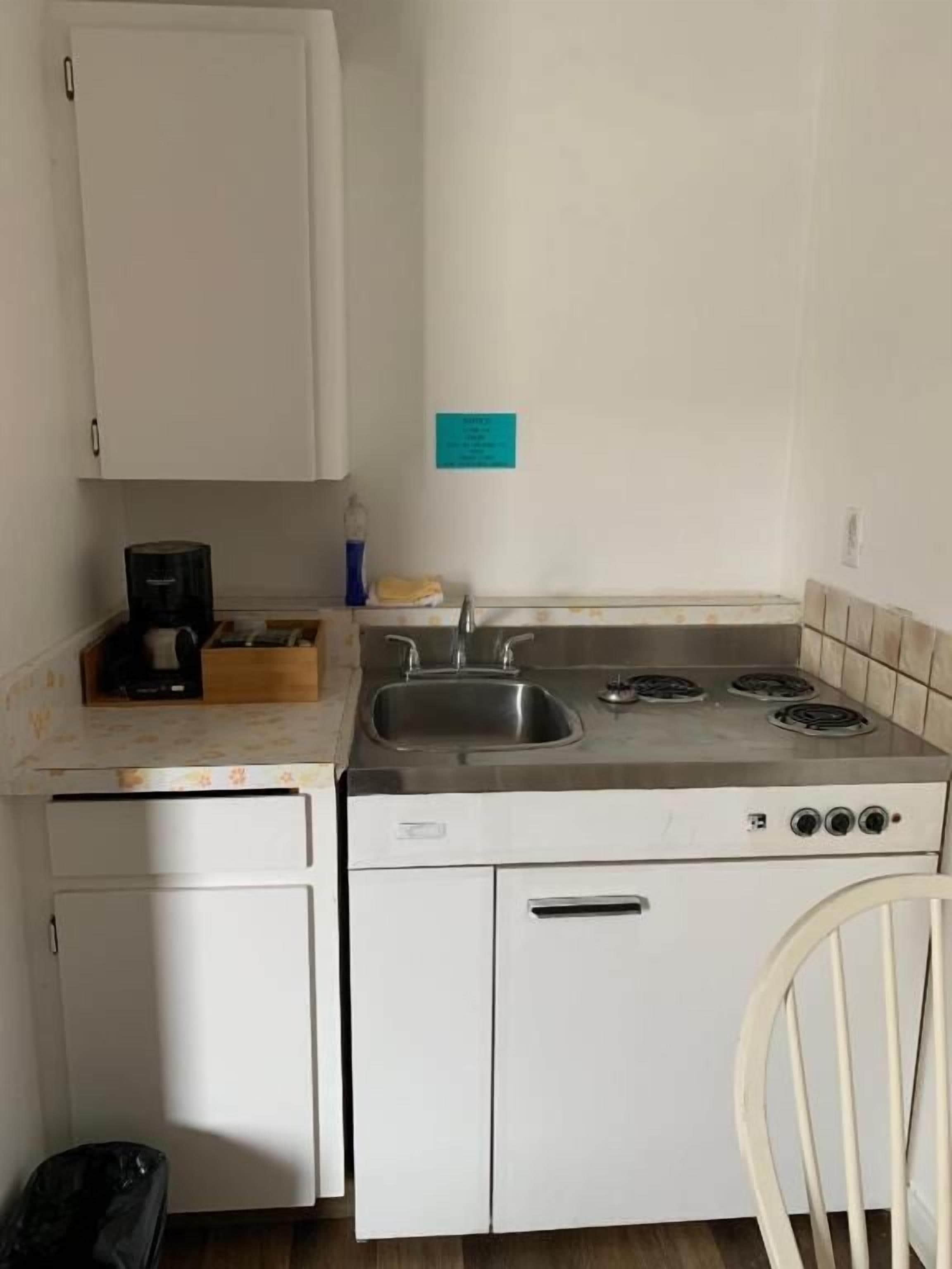 Una cocina compacta con estufa, pileta y armarios blancos.