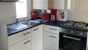 Eine kompakte Küche mit Mikrowelle, Kaffeemaschine, Toaster und Gasherd.