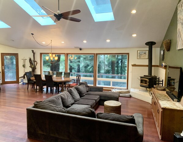 A spacious living area with a large sectional sofa, a dining table with chairs, and a fireplace. - Large house Up in the Redwoods perfect for large families. Pet friendly. (Fortuna)