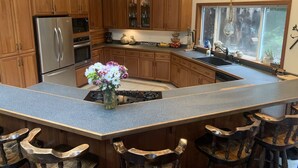 A kitchen with wooden cabinets, a stainless steel refrigerator, a gas stove, and a large island with bar stools. - Large house Up in the Redwoods perfect for large families. Pet friendly.  (Fortuna)