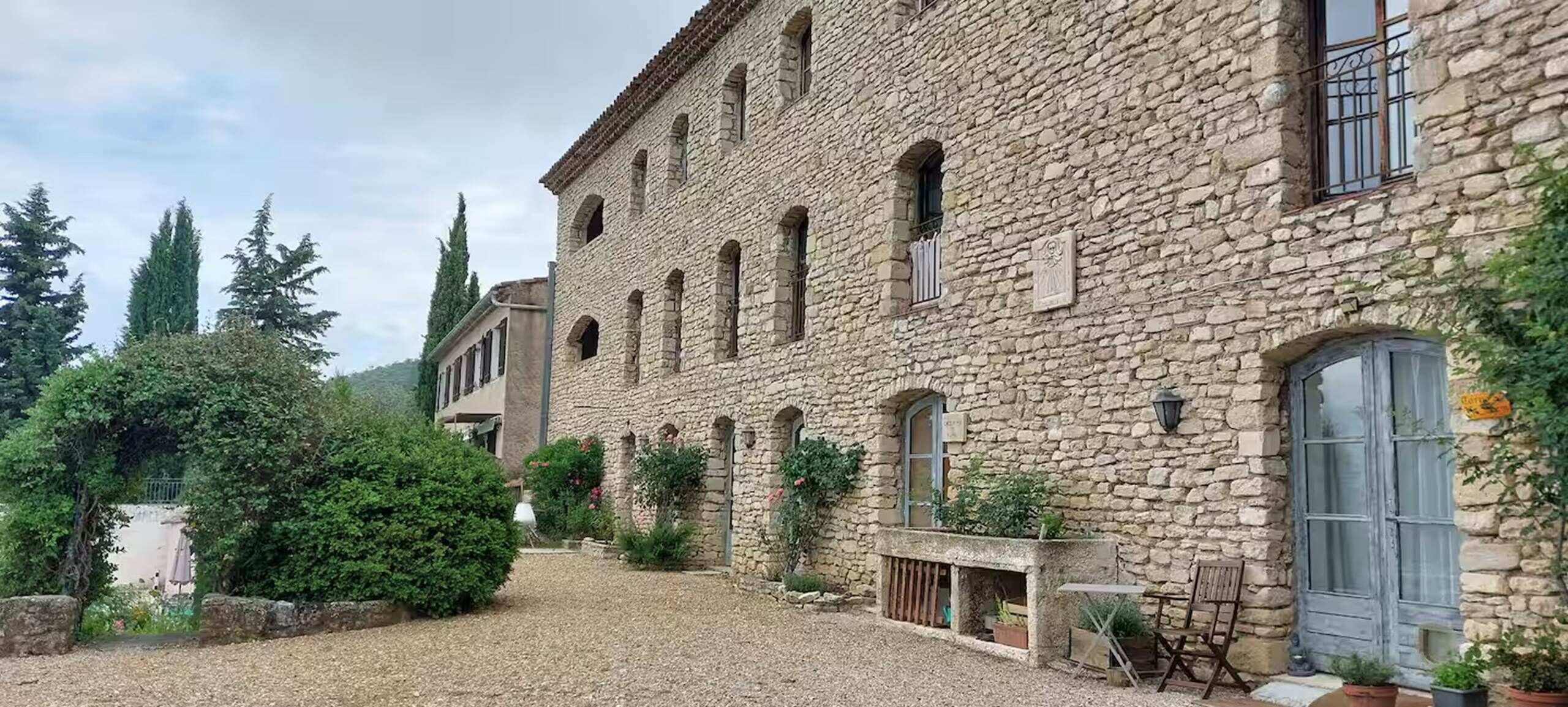 Un edificio de piedra con múltiples ventanas y un patio de grava.