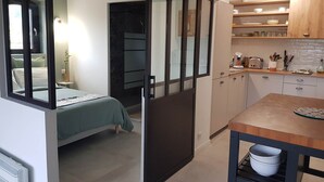 A compact room with a bed, a kitchenette, and a sliding door leading to another room. - "LE COSY LUBERON" - VIENS (Viens)