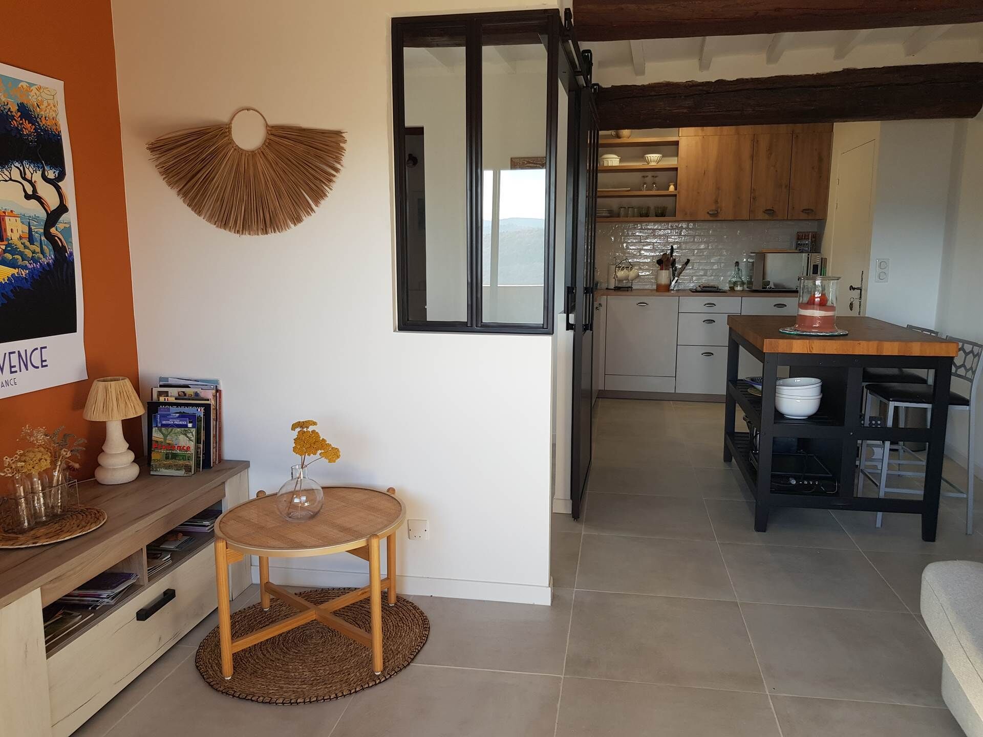A compact living space with a dining area, kitchen, and a large window.