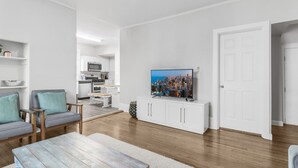 A modern living room with a flat-screen TV, a dining area, and a kitchen in the background. - Cozy W Front Porch DT Libertyville near Naval Base (Libertyville)