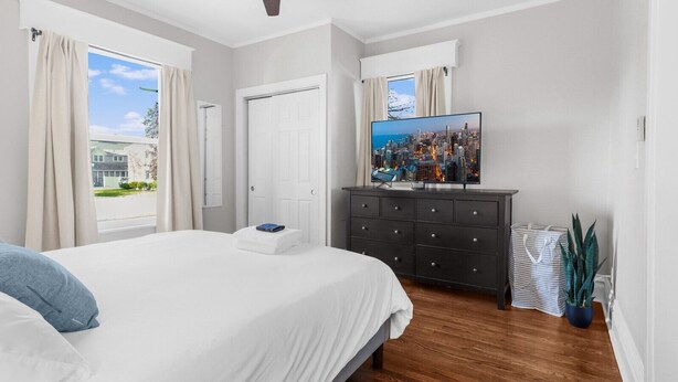 A bedroom with a bed, a dresser, a TV, and a window with curtains. - Cozy W Front Porch DT Libertyville near Naval Base (Libertyville)