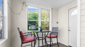 A room with a table and two chairs, a door, and a window with a view of a house and trees. - Cozy W Front Porch DT Libertyville near Naval Base (Libertyville)