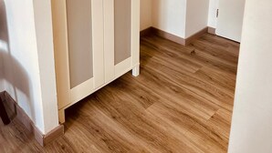 A room with a wooden floor, a white wardrobe with glass doors, and a white door in the background. - Upper-House (Aystetten)