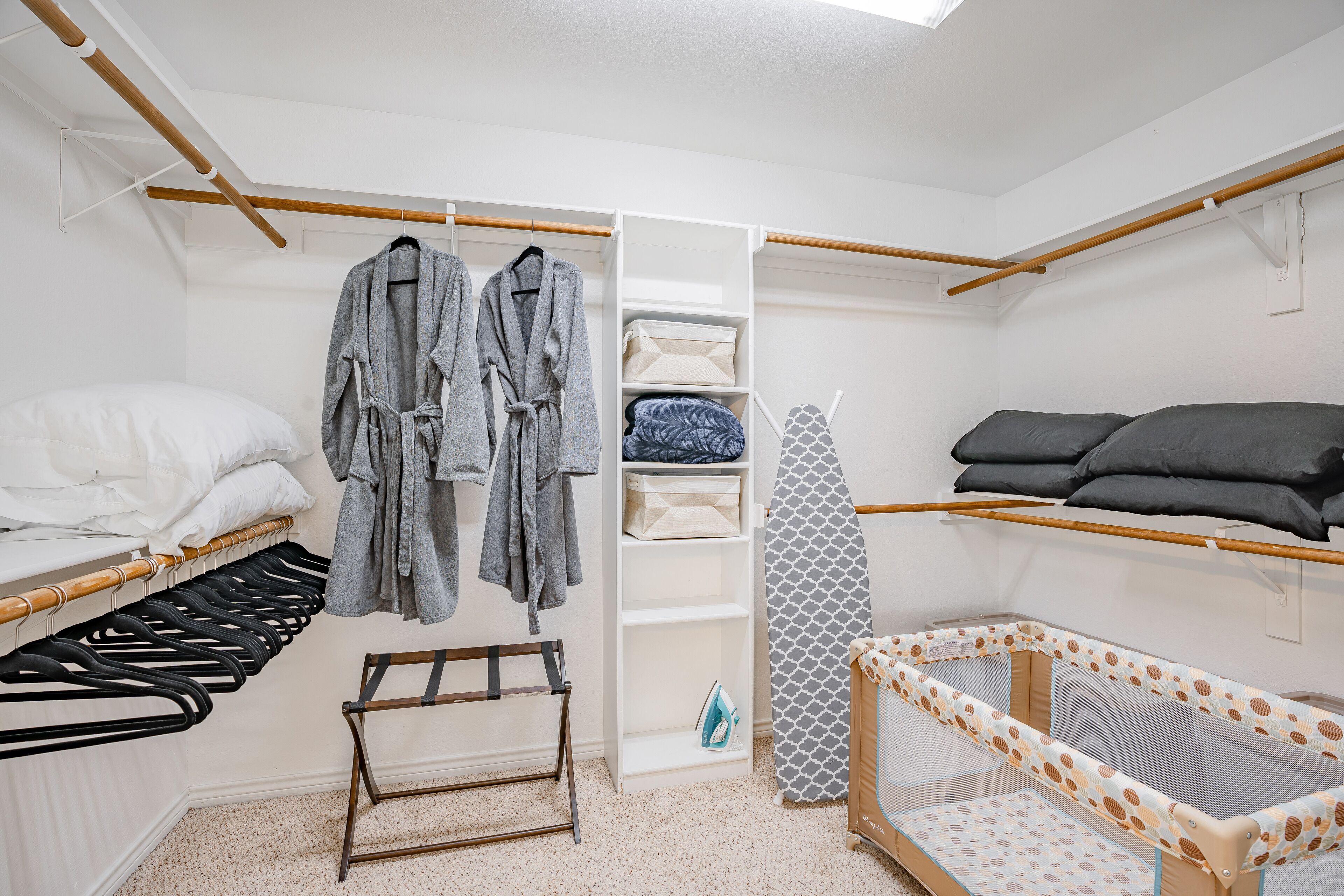 A neatly organized bedroom with a bed, a changing table, a wardrobe, and a crib.