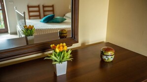 A wooden dresser with a mirror reflecting a bedroom. On the dresser, there are two small potted plants and a decorative jar. - La Casetta dei Gerani (Montemarano)