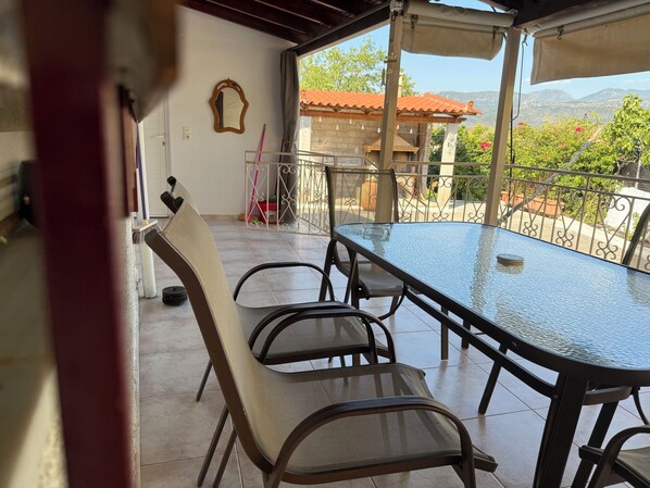 A covered outdoor patio with a glass table and four chairs.