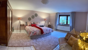 A bedroom with a bed, two bedside lamps, a window with curtains, and a view of the outdoors.