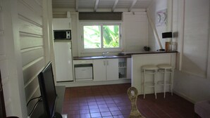 A compact kitchen with white cabinets, a microwave, and a window with a view of greenery.