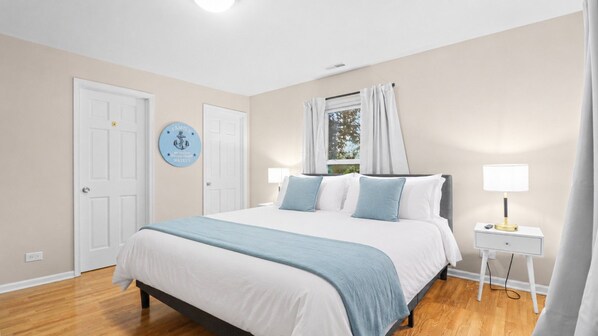 A bedroom with a bed, bedside tables, a window with curtains, and a wall decoration. - Charming apt in DT Libertyville - Near Naval Base (Libertyville)