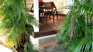 Un espace extérieur aménagé avec un banc et une table, entouré d’une végétation luxuriante.