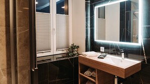 Un baño moderno con tocador de madera, un espejo grande y una planta en maceta.