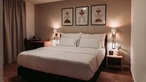 Una habitación de hotel moderna con una cama grande, dos mesitas de noche con lámparas y tres cuadros enmarcados en la pared.