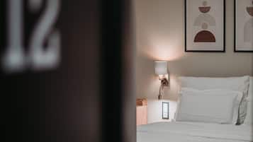 Una habitación de hotel con una cama, una mesita de noche, una lámpara y dos cuadros en la pared.