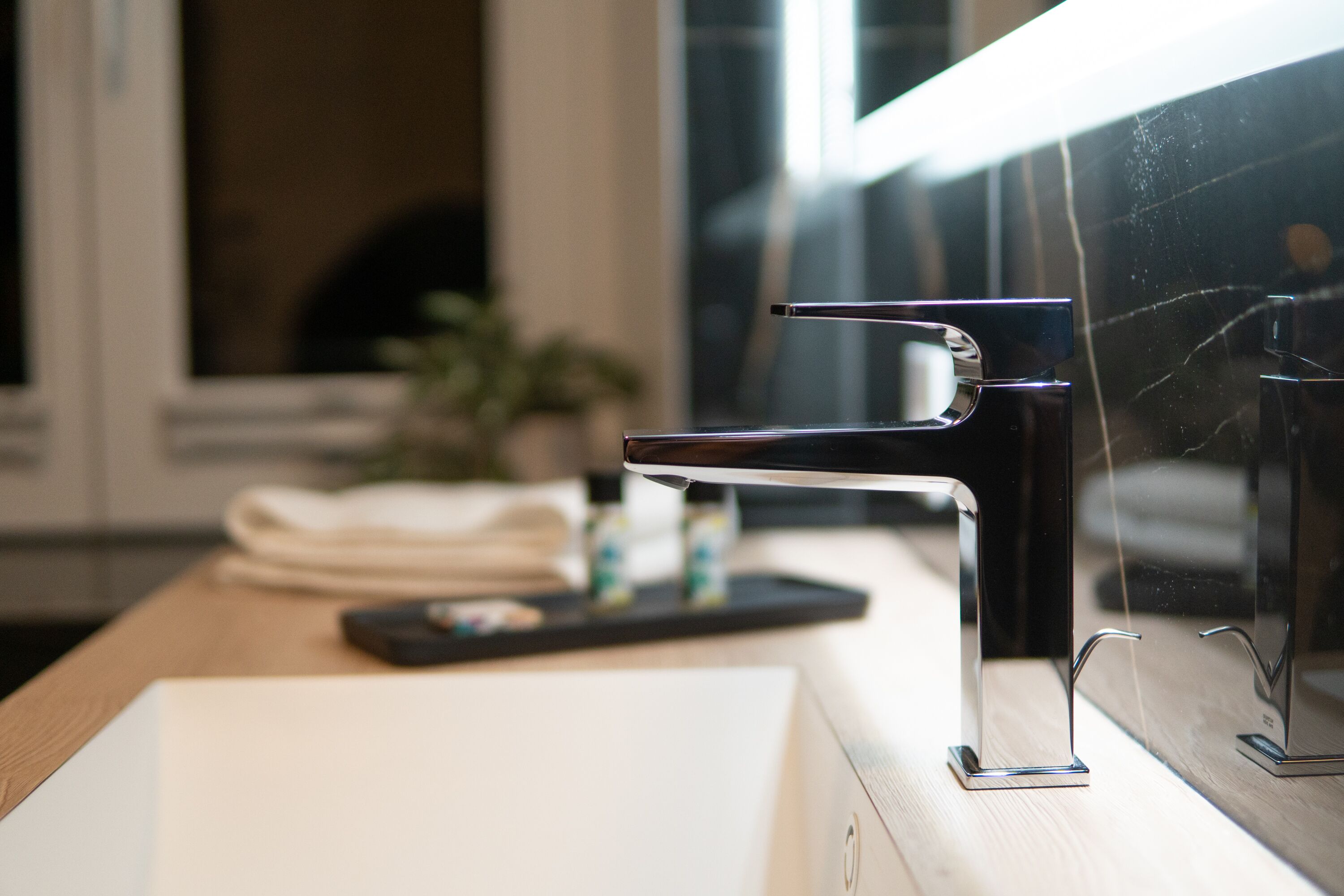 A modern bathroom with a sleek, chrome faucet on a white sink.