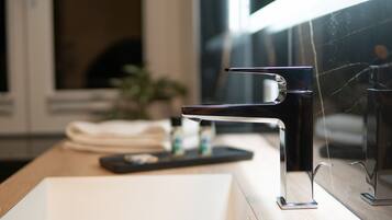 A modern bathroom with a sleek, chrome faucet on a white sink.
