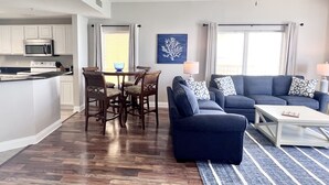 Ein modernes Wohnzimmer mit einem blauen Sofa, einem Couchtisch und einem Essbereich mit Tisch und Stühlen.
