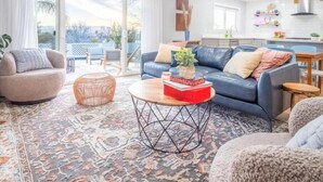 A modern living room with a blue sofa, a round coffee table, and a patterned rug.