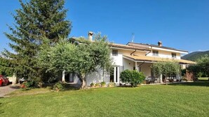 A two-story house with a well-maintained lawn and a parked car in front. - Green Paradise (Introdacqua)