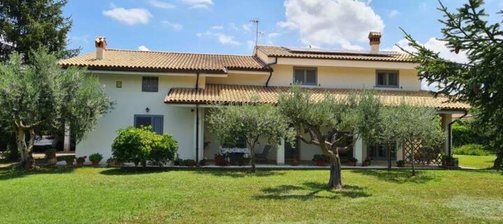 A two-story house with a tiled roof, a front porch, and a well-maintained lawn.