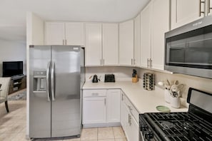 A modern kitchen with white cabinets, a stainless steel refrigerator, a microwave, and a stove. - Home W/ Large Deck, Libertyville - Near Naval Base (Libertyville)