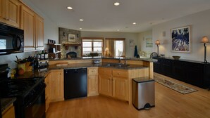 A spacious kitchen with wooden cabinets, granite countertops, a built-in dishwasher, and a central island.