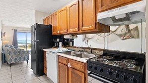 Eine Küche mit Holzausstattung, einem schwarzen Kühlschrank, einem Herd und einem Spülbecken.