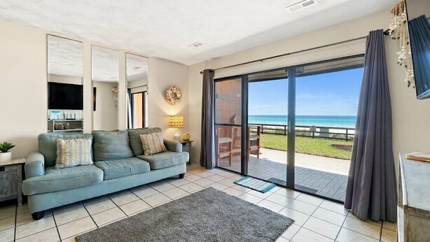 Ein modernes Wohnzimmer mit Sofa, Couchtisch und einer großen Glasschiebetür, die auf einen Balkon mit Meerblick führt.