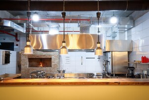 Una cocina moderna con horno de ladrillo, electrodomésticos de acero inoxidable, lámparas colgantes y encimera de madera.
