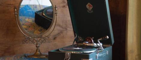 A vintage gramophone in a green case on a patterned tablecloth.
