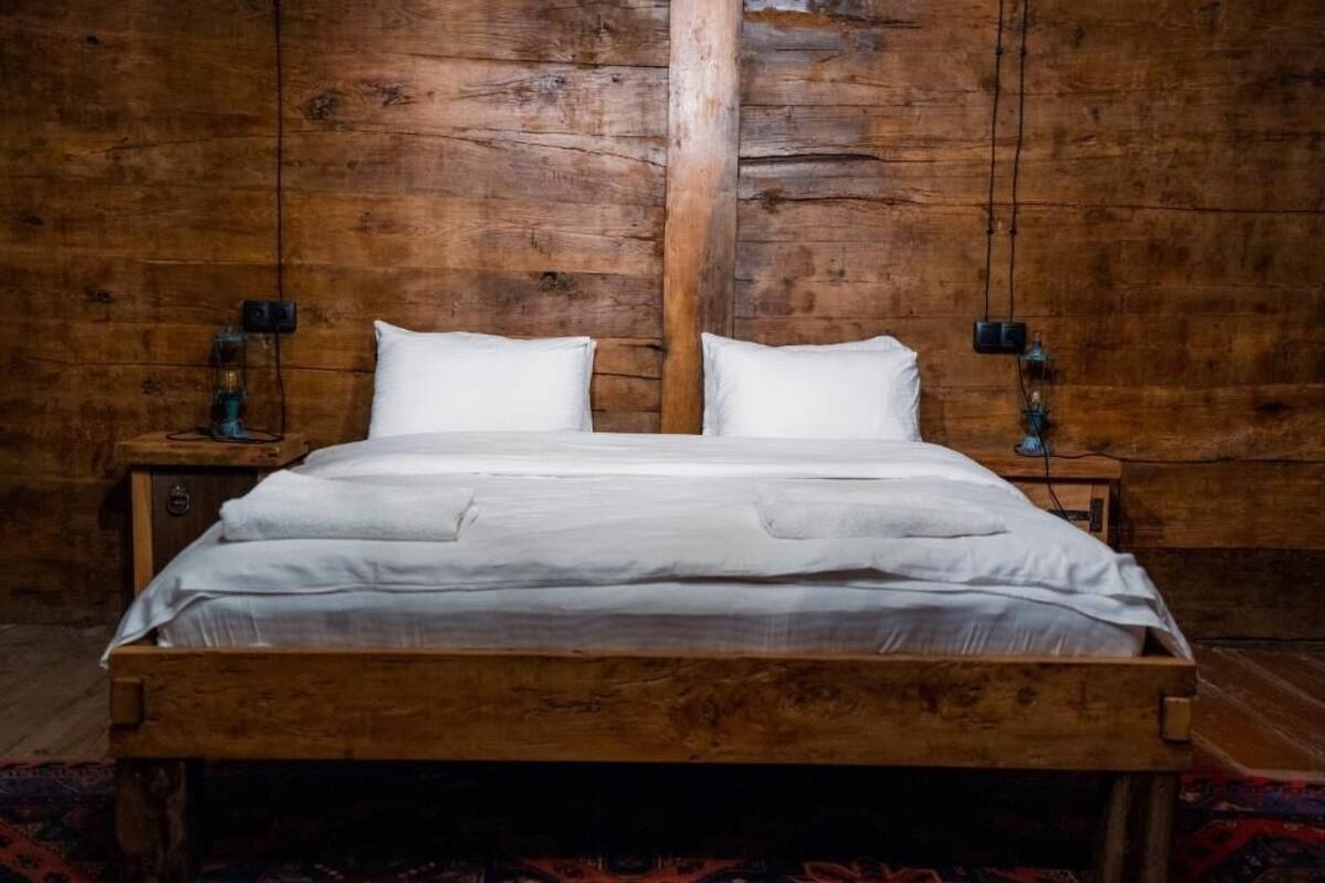 A wooden bed with white linens in a room with wooden walls and nightstands.