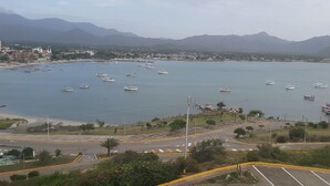 A coastal town with a marina filled with boats, a road with a roundabout, and mountains in the background. - Casa Caraibe Playa el Agua Vacances Inoubliable au Soleil (Antolin del campo)