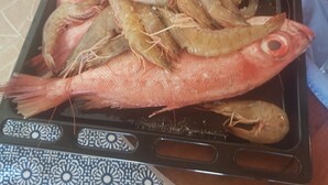 Un plat amb marisc cuinat, incloent peix i gambes, damunt una tovallola amb dibuixos.