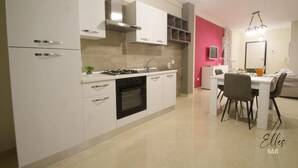 Una cocina moderna con armarios blancos, estufa a gas y un comedor con mesa y sillas.