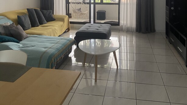 Een moderne woonkamer met een bank, een poef en een kleine tafel.