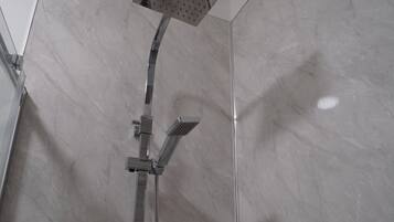 Une douche moderne dotée d’un pommeau de douche carré et d’un pommeau de douche à main.