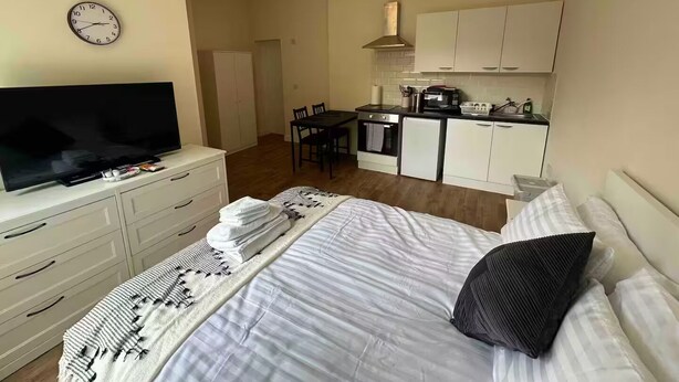 Une chambre d’hôtel compacte comprenant un lit, une télévision, une petite kitchenette et un coin repas.