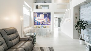 Ein modernes Wohnzimmer mit einer Ledersofa, einem Essbereich mit Tisch für vier Personen und einem großen Stadtbild-Wandgemälde.