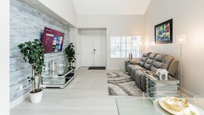 Ein modernes Wohnzimmer mit Fernseher, Sofa und Dekorationselementen.