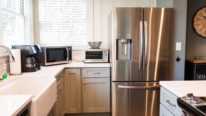 A modern kitchen with stainless steel appliances, including a refrigerator, microwave, and coffee maker. - Charming 1920's House - pet friendly, 45 minutes from beach & attractions! (Sanford)
