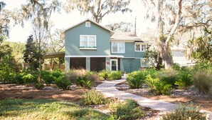 A two-story house with a covered porch and a driveway leading to the garage. - Charming 1920's House - pet friendly, 45 minutes from beach & attractions! (Sanford)