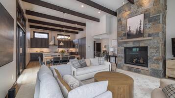 A spacious living area with a fireplace, modern furniture, and a kitchen in the background.