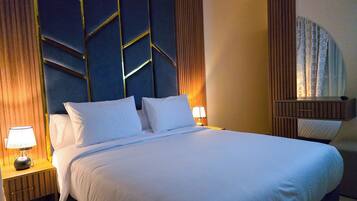 A hotel room with a large bed, a nightstand with a lamp, a wooden headboard, and a mirror.