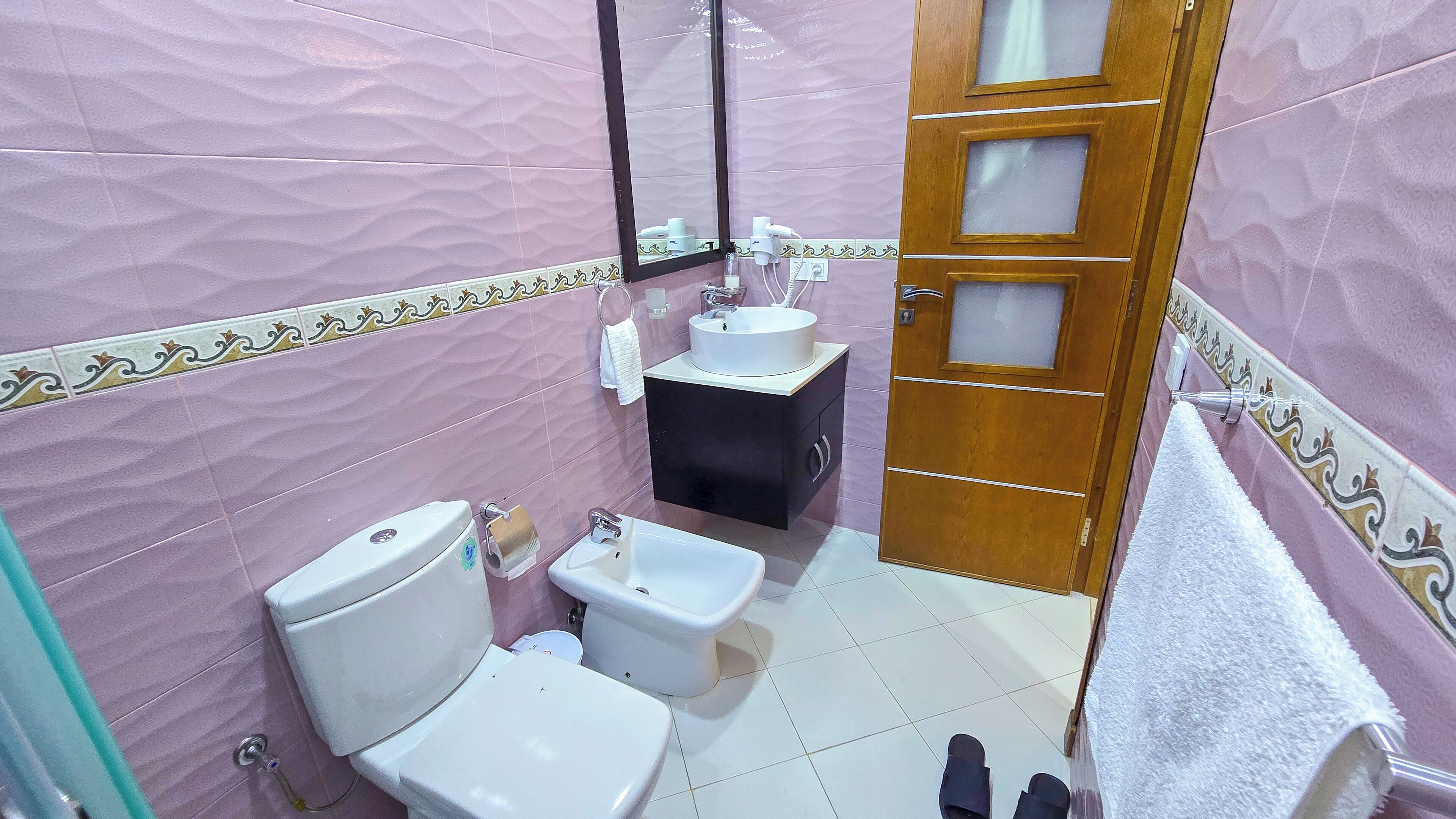 A bathroom with a toilet, bidet, sink, and a mirror.