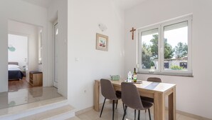Un espace repas moderne avec une table en bois, deux chaises et une fenêtre donnant sur la forêt.