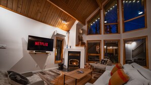 Una sala de estar acogedora con chimenea, un televisor de pantalla plana y un área de descanso confortable.